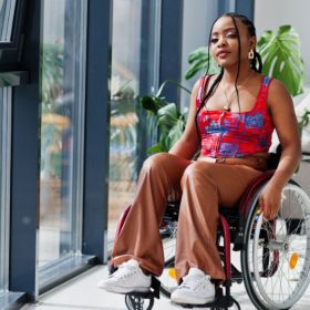 Teenage female, sitting in a wheelchair looking at the camera with a proud look on her face.
